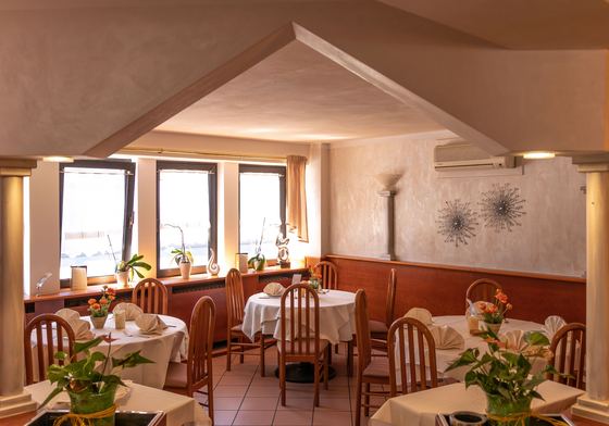 Heller Speiseraum mit weißen Tischdecken, Pflanzen und Blumen