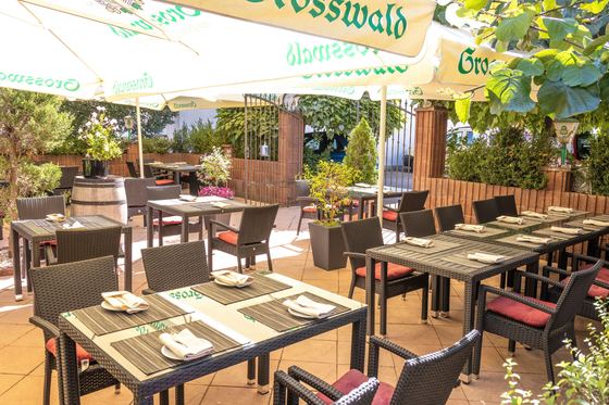 Großer Biergarten mit Sonnenschirmen und gedeckten Tischen
