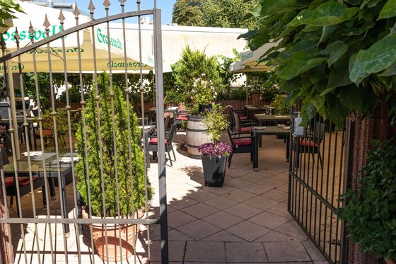 Eingang zum begrünten Biergarten mit gedeckten Tischen